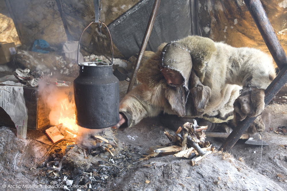 Chukchi reindeer herder, Grisha Rahtyn, tends a fire he has lit to melt a pot of ice in his Yaranga. Chukotskiy Peninsula, Chukotka, Siberia, Russia. 2010